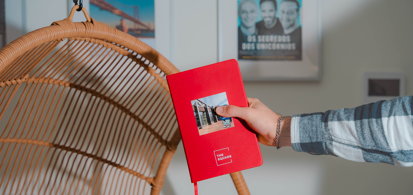 Red The Square book held beside a wicker chair
